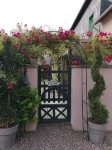a black gate with pink flowers and plants at La Cour Du Puits Chambre Rooibos in Cormeilles
