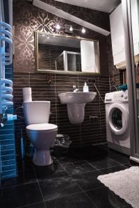 a bathroom with a toilet and a sink and a washing machine at Apartament z widokiem in Gdynia