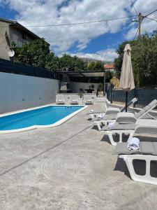 una piscina con tumbonas y sombrilla en Apartments Antini en Solin