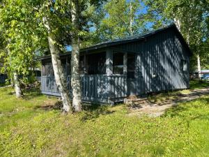 eine schwarze Hütte auf einem Feld mit Bäumen in der Unterkunft Air-Dale Lodge in Hawk Junction