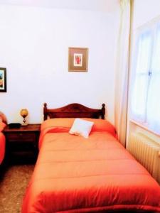 1 dormitorio con cama roja y ventana en Ruta del quijote, en Campo de Criptana