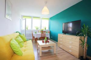 een woonkamer met een gele bank en een tv bij Apartament Parkowy in Wałbrzych