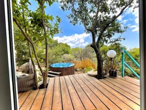 a wooden deck with a hot tub and a tree at Solara Cabin in Amirim