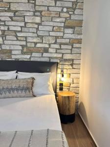 a bedroom with a brick wall with a bed and a table at Peri Elxis Luxury Suites in Mouresi