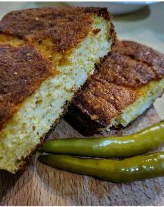 two slices of bread and a green pickle on a cutting board at Raković Katun in Berane