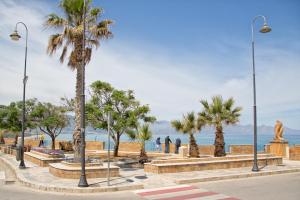 バレストラーテにあるAlta Marea Sea Apartmentsの海のそばのヤシの木と像のある公園