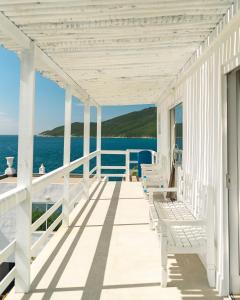 a white porch with white benches on the water at Casa Santorini Terrace in Arraial do Cabo