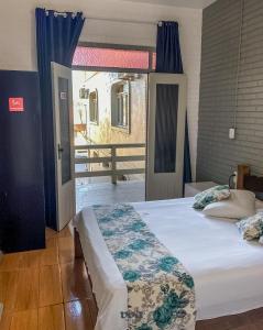 1 dormitorio con 1 cama y puerta a un balcón en Pousada Brisa de Gramado, en Gramado