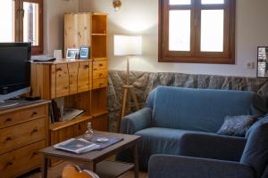 a living room with a blue couch and a tv at Kuca pod Rudnikom in Trudelj