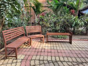 two wooden benches sitting on a brick patio at Nivaant @ Vicharays in Alibaug