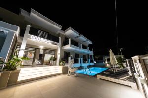 a villa with a swimming pool at night at Ammos Luxury Apartments in Nea Vrasna