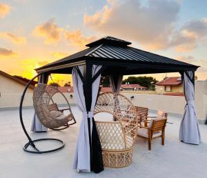 einen Pavillon auf einer Terrasse mit Stühlen und einem Tisch in der Unterkunft הפינה של טלי בנהריה - אירוח וספא בריאות מחומם in Naharija