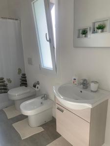 a white bathroom with a sink and a toilet at Angolo paradiso in Castelvetrano Selinunte