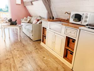 una cocina con armarios blancos y un sofá en una habitación en Studio de charme avec piscine de relaxation en Moyaux