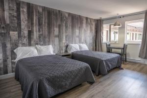 1 dormitorio con 2 camas y pared de madera en Le 2020 Charlevoix, en La Malbaie