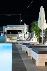 uma piscina com guarda-sol e cadeiras e uma piscina em Ammos Luxury Apartments em Nea Vrasna