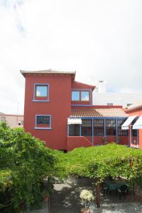 un edificio rojo con un jardín delante de él en Villa Perestelo en Los Sauces