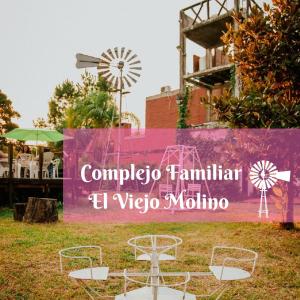 a sign for a restaurant with chairs and a windmill at Complejo Familiar EL VIEJO MOLINO in Paso de la Patria