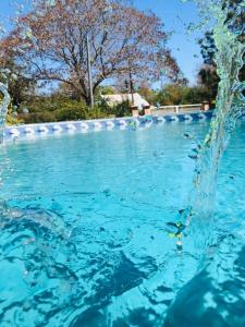 a pool of blue water with a fountain at Complejo Familiar EL VIEJO MOLINO in Paso de la Patria