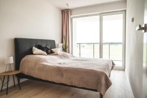 ein Schlafzimmer mit einem Bett und einem großen Fenster in der Unterkunft Apartament w Westin House Resort Kołobrzeg in Kołobrzeg