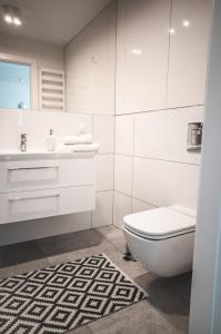 ein weißes Bad mit einem WC und einem Waschbecken in der Unterkunft Apartament w Westin House Resort Kołobrzeg in Kołobrzeg