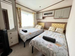 Habitación pequeña con 2 camas y ventana en Honeysuckle Hot Tub Lodge, en South Cerney