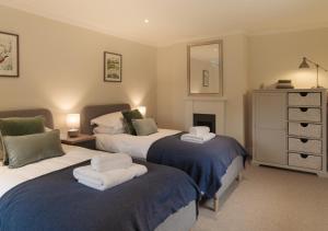 a bedroom with two beds and a dresser with a mirror at Garden House at Woodhall Estate in Hertford