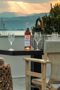 ナフプリオにあるEudokia Pensionの- テーブルの上に置かれたウイスキー1本とワイングラス2杯