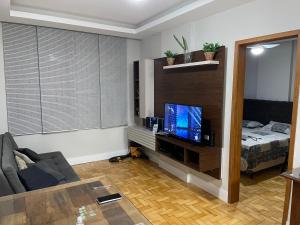 a living room with a television and a bed at Apartamento Icarai Praia in Niterói