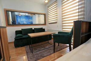 a living room with a green couch and a table at Apartman KUTAK Jahorina in Jahorina