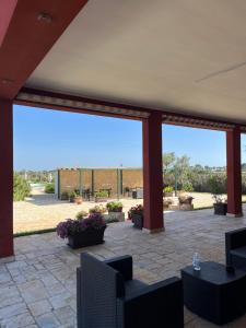 eine Terrasse mit Stühlen, Tischen und einem großen Fenster in der Unterkunft Agriturismo Caranna in Torre Lapillo
