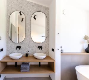 a bathroom with two sinks and two mirrors at Sauerland Lodge - Haus Juliana in Winterberg