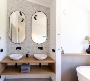 a bathroom with two sinks and two mirrors at Sauerland Lodge - Haus Julius in Winterberg +12 photos