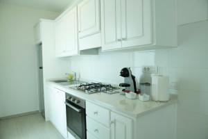 cocina blanca con fogones y armarios blancos en Casa Antonello, en Golfo Aranci