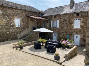 a patio with chairs and an umbrella in front of a building at Chambre d'hotes Bessiard in Laparrouquial