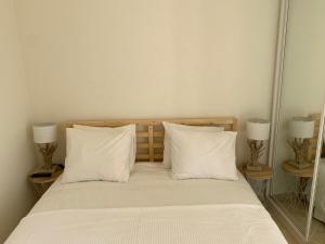 a bed with white sheets and pillows and two lamps at Maria Luísa in Olhos de Água