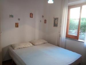 een kleine witte slaapkamer met een bed en een raam bij Appartamento Airone in Piraino