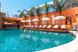 a large swimming pool with chairs and umbrellas at Genesis Hotel&Spa Alaçatı in Alaçatı