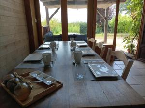 une longue table en bois avec des assiettes et des verres dans l'établissement Cadol'Ain, à Servignat