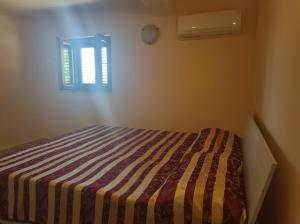 1 dormitorio con 1 cama con manta a rayas y ventana en La casa dei nonni, en Montecorice