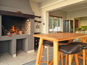 a kitchen with a wooden table and a fireplace at Die Braaihuis, sleeps 6, Central and Fabulous! in Gordonʼs Bay