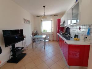 ブリアーティコにあるVilla Sabbiaの赤いキャビネットとテーブル付きのキッチンが備わります。