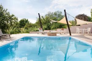 a swimming pool with chairs and a table and umbrella at Villa Daniela in Úvaly