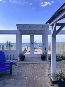a white pergola with people walking on the beach at By The Sea Guests Bed & Breakfast and Suites in Dennis Port