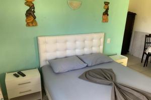 a bedroom with a large bed with a white headboard at Hotel Pousada Rancho Fundo in Camaçari