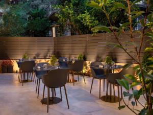 a patio with tables and chairs in front of a fence at ASKLIPIOS LUXURY ROOMS in Nafpaktos