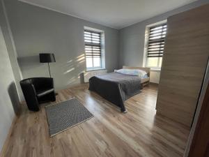 sypialnia z łóżkiem i krzesłem oraz 2 oknami w obiekcie Apartamenty Trzciana w mieście Rzeszów