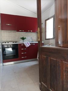 a kitchen with red cabinets and a stove at Appartamento Oliver Villasimius in Villasimius +1 photo