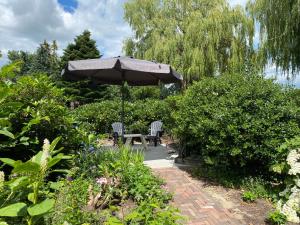 een tafel en stoelen onder een parasol in een tuin bij De Drie Berken in Klazienaveen