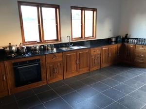 una cocina con armarios de madera, fregadero y ventanas en Villa Rosa East Bali, en Karangasem